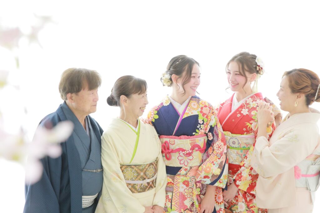振袖姿の女性2名と着物姿の家族が一緒に撮影した記念写真