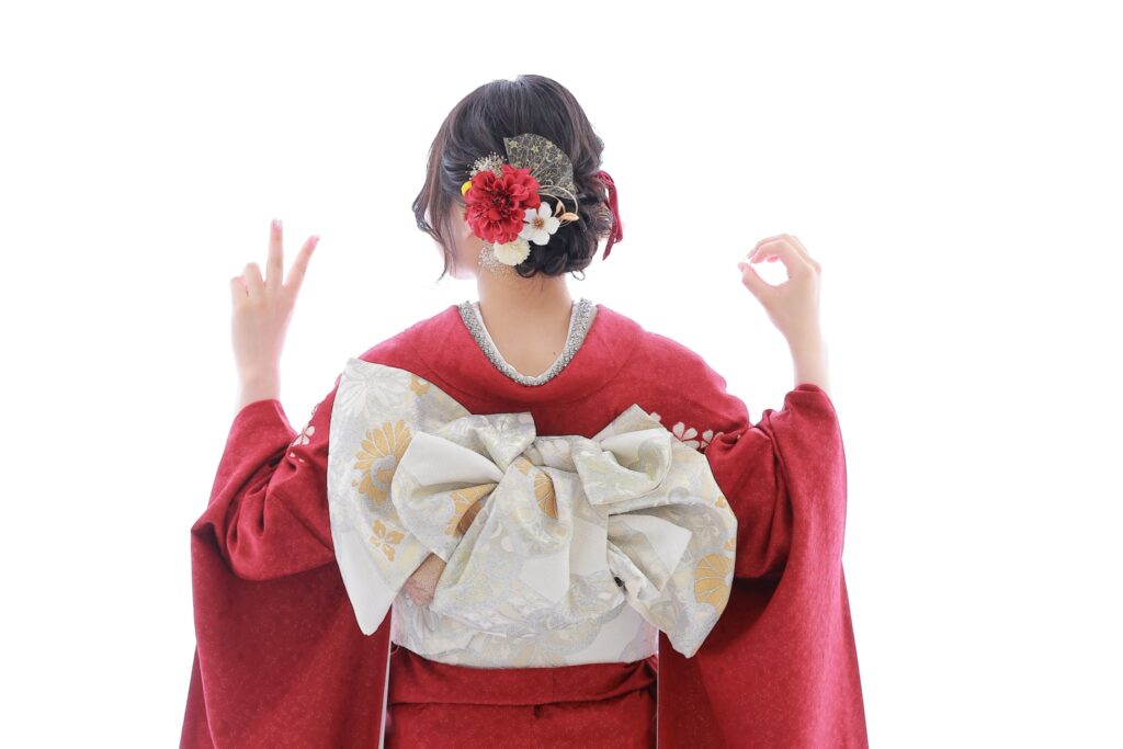 赤い振袖の後ろ姿と白とゴールドの華やかな帯結びと髪飾り